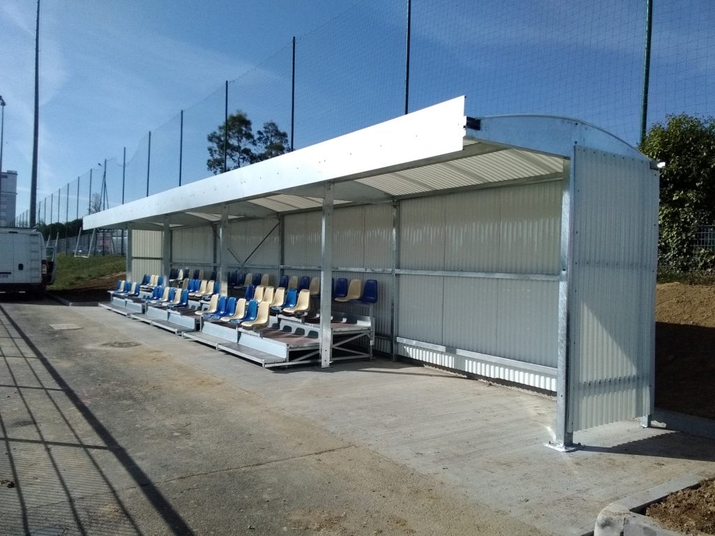 White-roofed spectator shelter fitted with three rows of grandstand seats