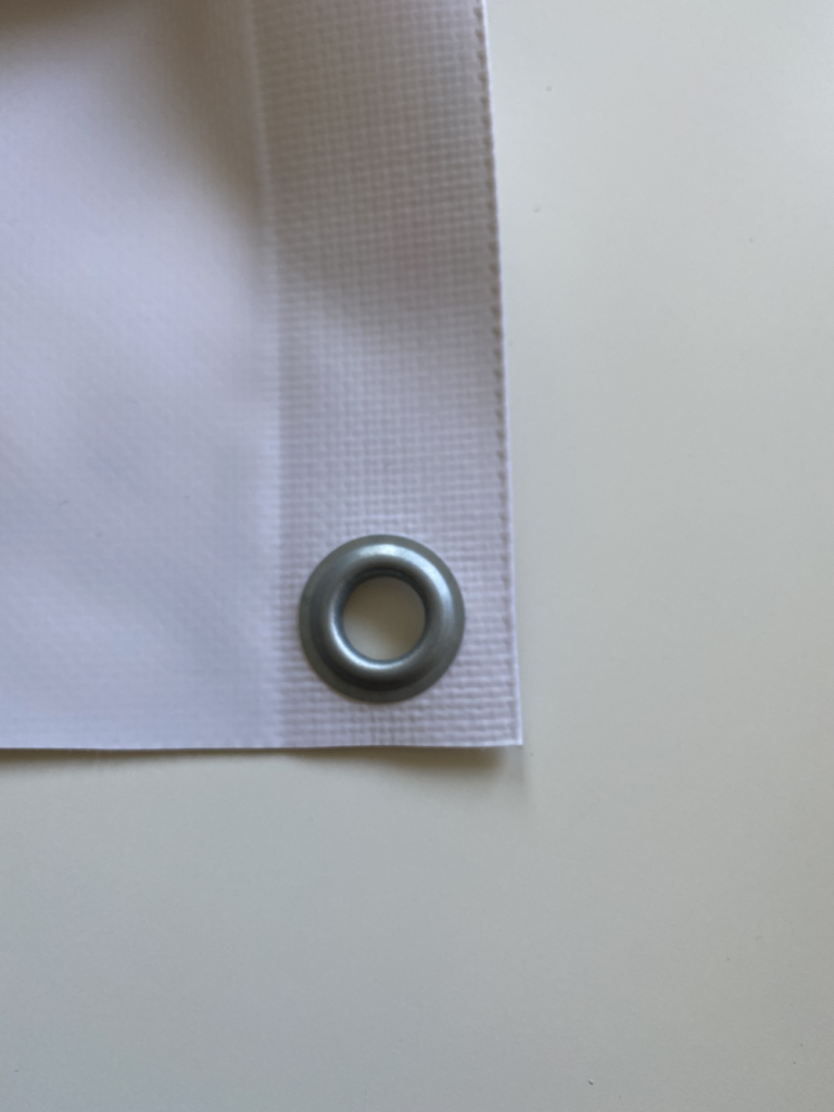 Close-up of a metal eyelet fitted in the hem of a grandstand cover