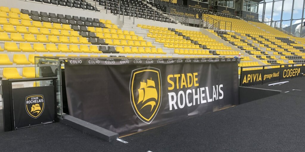 Advertising cover printed in Stade Rochelais colours at the front of a grandstand