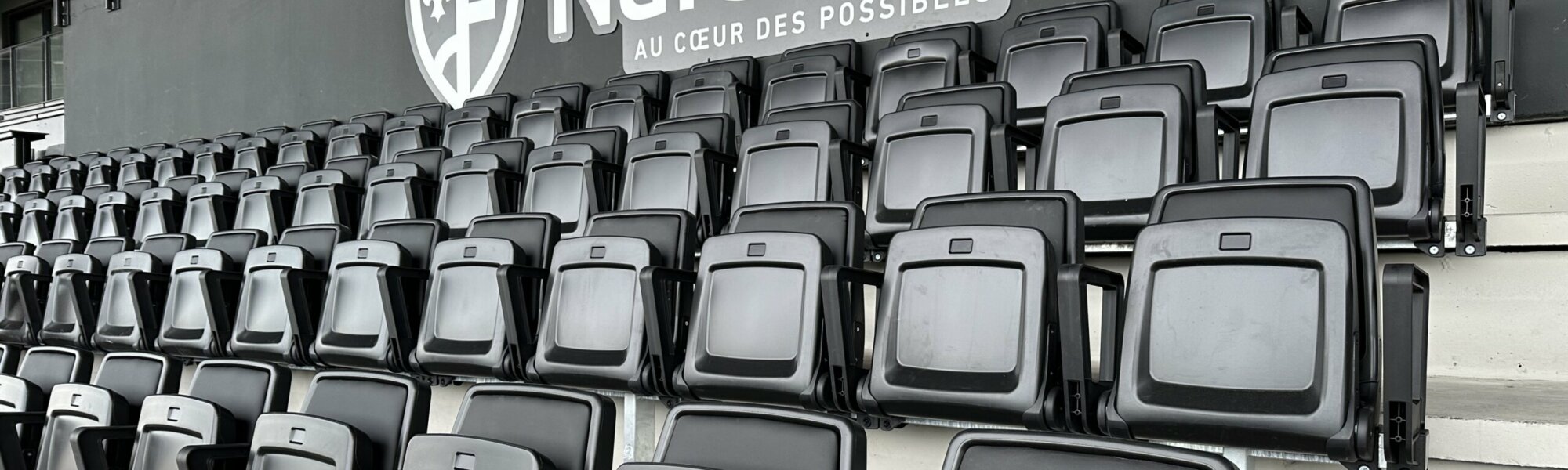 Sièges gris et noirs alignés devant l'enseigne murale Narbonne au cœur des possibles