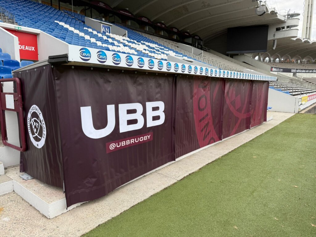 Printed UBB fabric dressing along the full length of a dugout at the edge of the pitch
