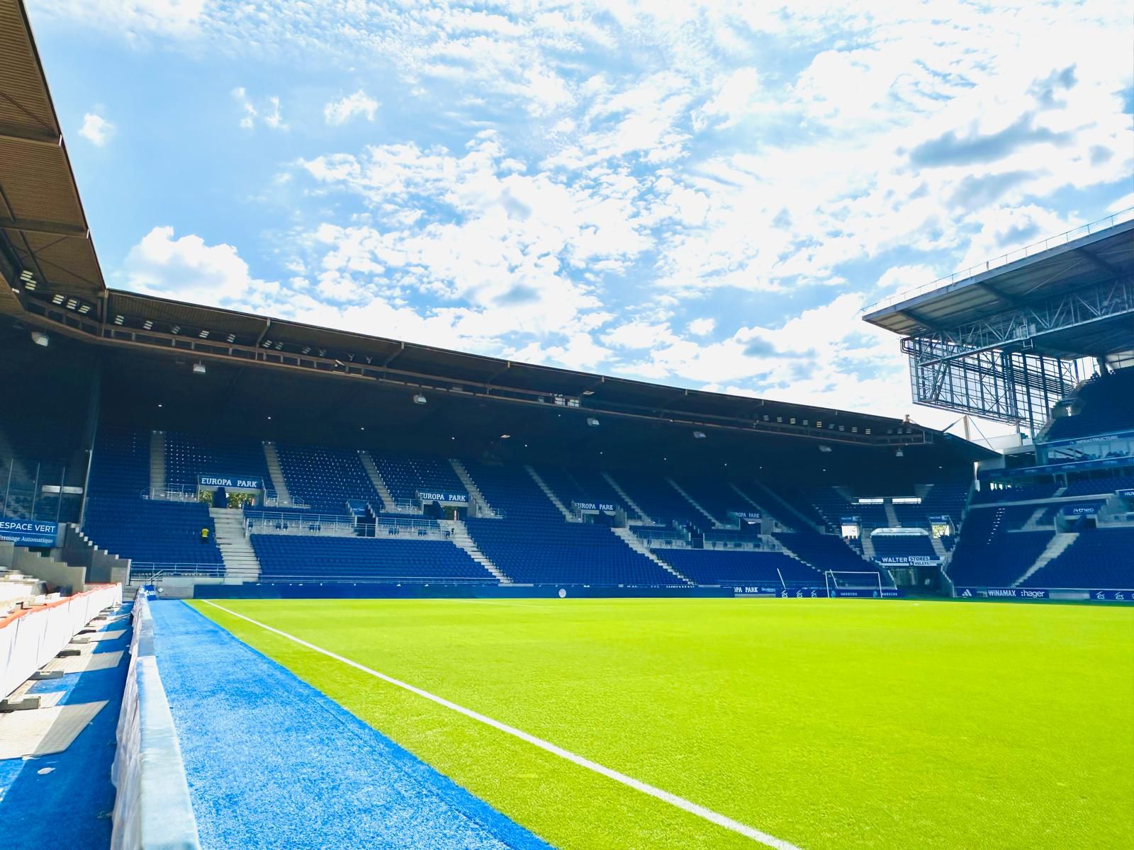 Pitch-level view along the blue track, stands fitted with blue seats all around the ground